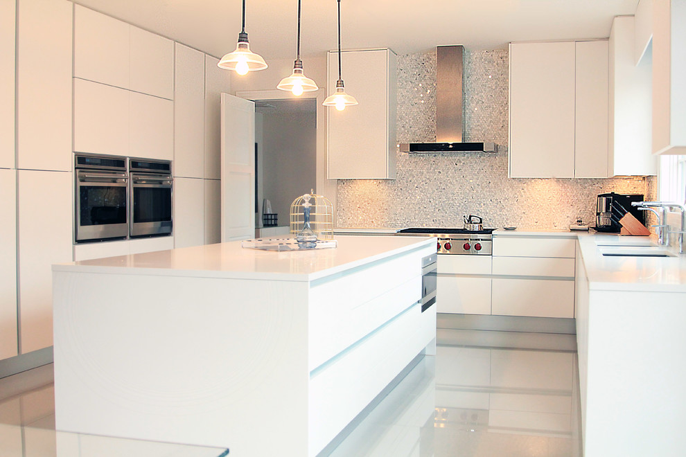 Foto på ett stort funkis u-kök, med släta luckor, vita skåp, stänkskydd med metallisk yta, stänkskydd i metallkakel, vita vitvaror, marmorgolv och en köksö