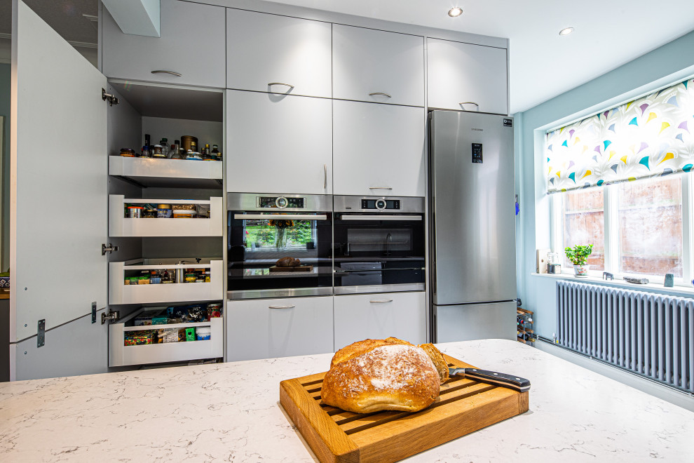 Large contemporary u-shaped kitchen/diner in Other with a double-bowl sink, flat-panel cabinets, grey cabinets, quartz worktops, grey splashback, porcelain splashback, integrated appliances, lino flooring, a breakfast bar, grey floors and white worktops.