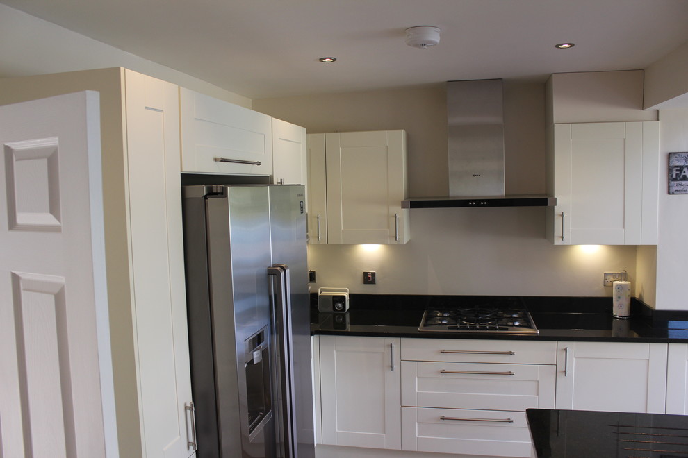 Photo of a medium sized farmhouse l-shaped kitchen/diner in Hertfordshire with a submerged sink, shaker cabinets, beige cabinets, granite worktops, stainless steel appliances and an island.