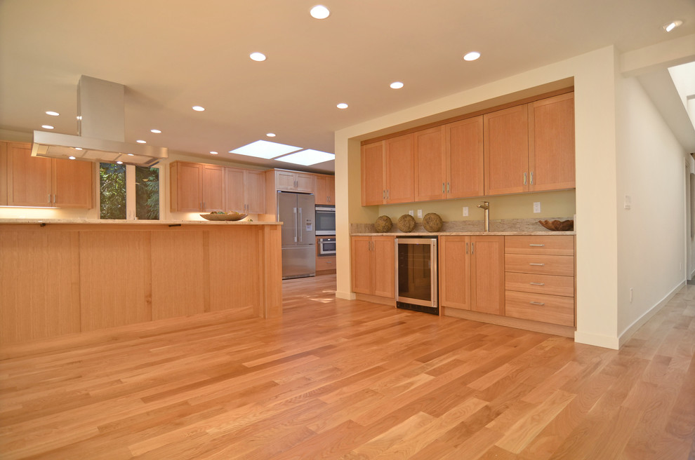 Klassisk inredning av ett kök, med en undermonterad diskho, luckor med infälld panel, skåp i mellenmörkt trä, granitbänkskiva, flerfärgad stänkskydd, stänkskydd i sten och rostfria vitvaror