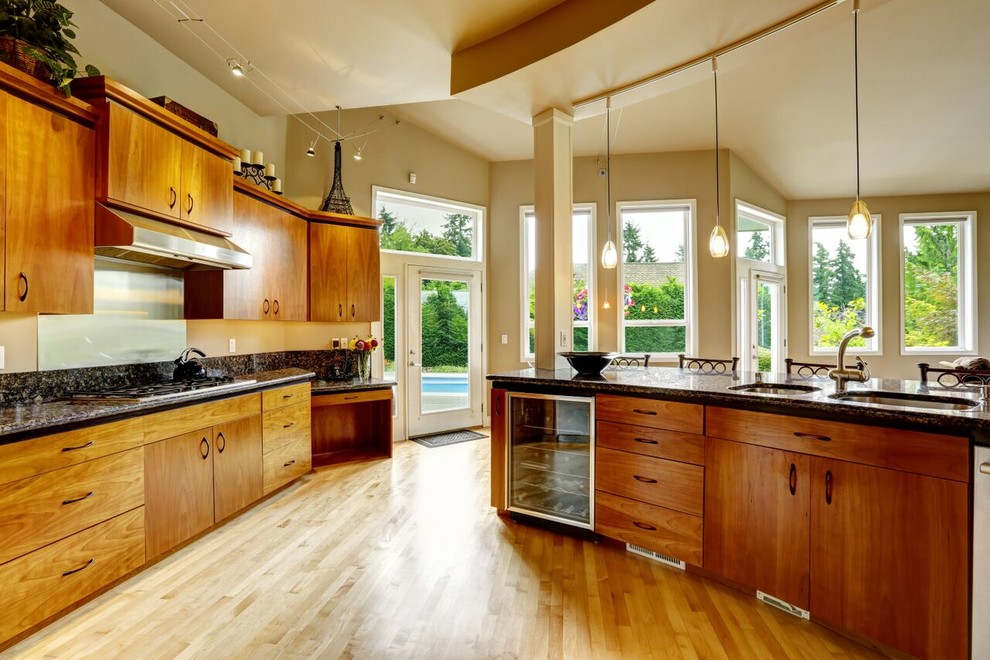 Photo of a contemporary kitchen in Chicago with an integrated sink, flat-panel cabinets, medium wood cabinets, laminate countertops, beige splashback, medium hardwood flooring and a breakfast bar.