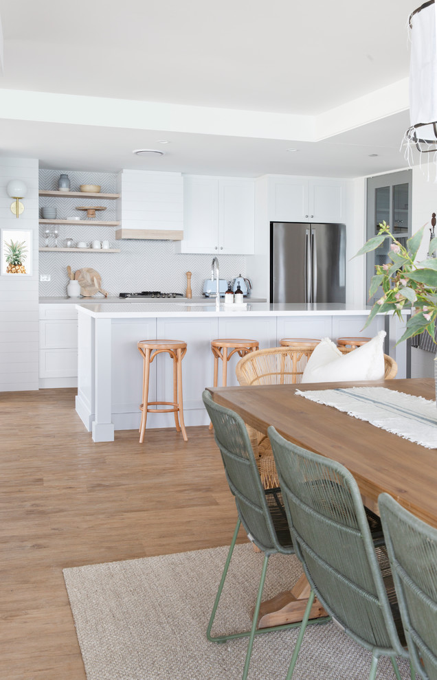 Idéer för att renovera ett stort maritimt vit vitt kök, med en undermonterad diskho, skåp i shakerstil, grå skåp, bänkskiva i kvarts, beige stänkskydd, stänkskydd i porslinskakel, rostfria vitvaror, vinylgolv, en köksö och brunt golv