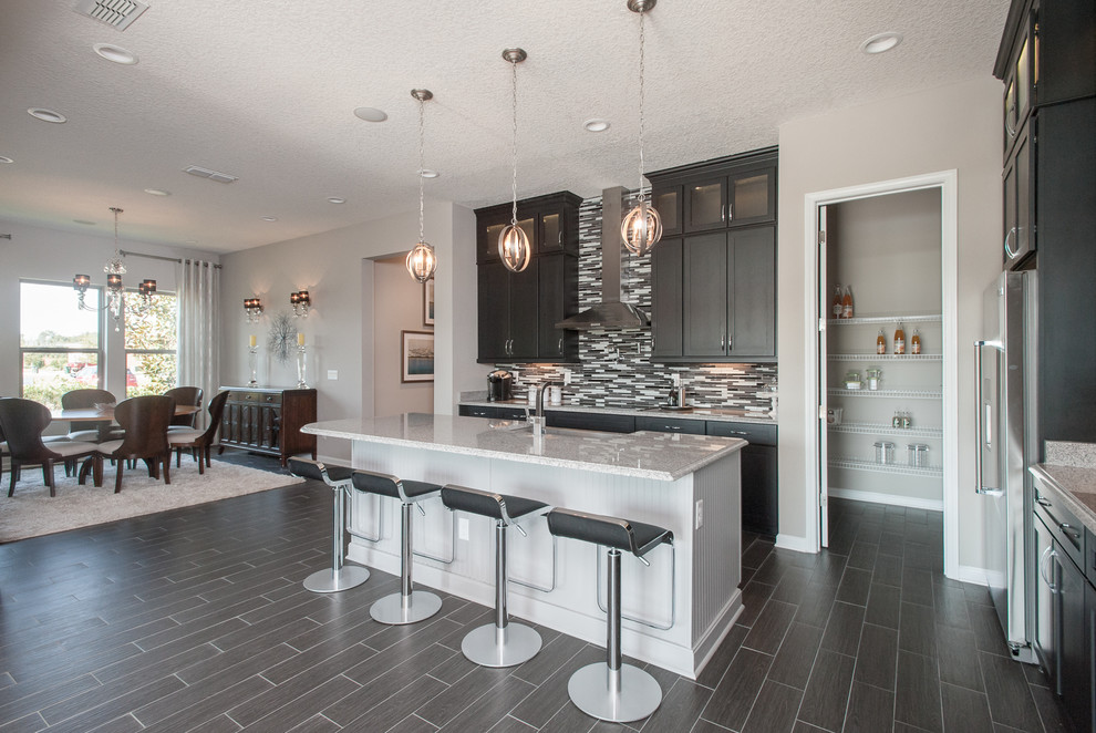 Example of a large minimalist galley ceramic tile eat-in kitchen design in Jacksonville with a farmhouse sink, flat-panel cabinets, black cabinets, granite countertops, multicolored backsplash, stainless steel appliances, an island and matchstick tile backsplash