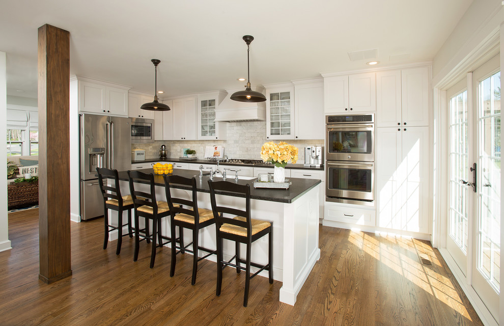 Example of a large cottage l-shaped medium tone wood floor and brown floor eat-in kitchen design in DC Metro with a farmhouse sink, shaker cabinets, white cabinets, granite countertops, white backsplash, marble backsplash, stainless steel appliances and an island