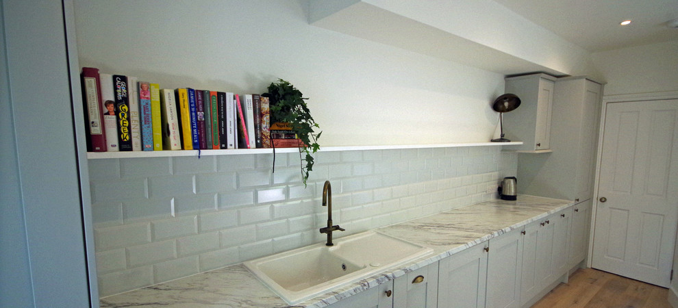 Idéer för att renovera ett mellanstort vintage vit linjärt vitt kök och matrum, med en enkel diskho, skåp i shakerstil, grå skåp, laminatbänkskiva, vitt stänkskydd, stänkskydd i keramik, integrerade vitvaror och mellanmörkt trägolv