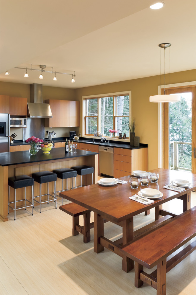 Cette photo montre une cuisine américaine tendance en bois brun avec un électroménager en acier inoxydable et un placard à porte plane.