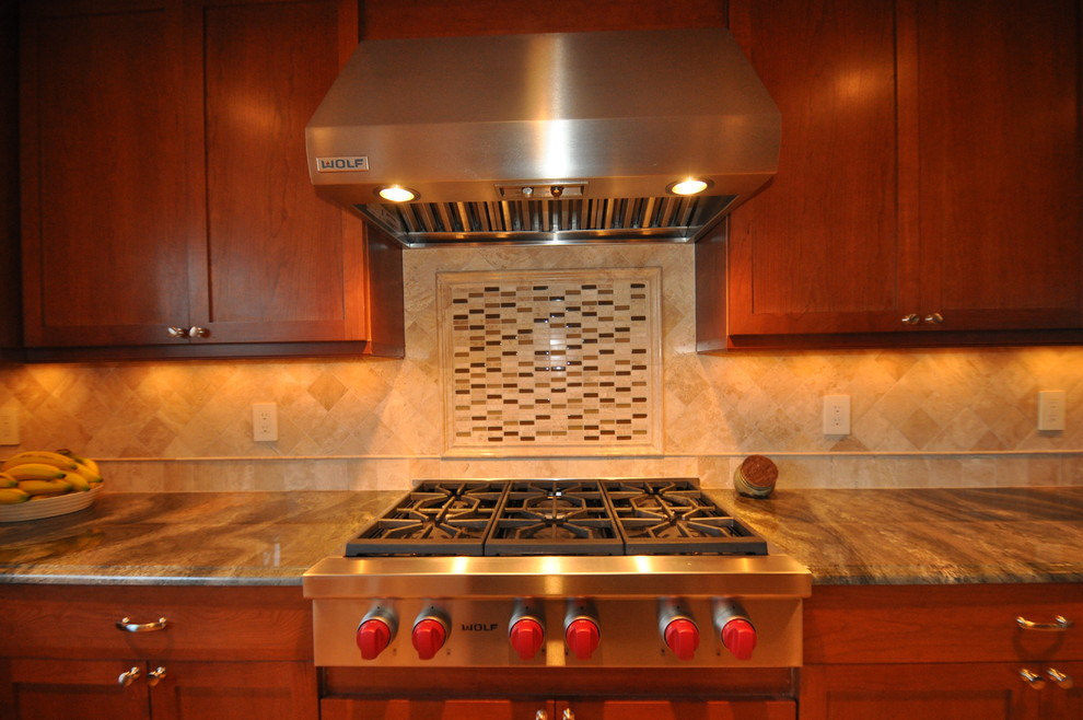 Exemple d'une cuisine tendance en bois foncé avec un placard avec porte à panneau encastré, un plan de travail en granite, une crédence beige, une crédence en mosaïque et un électroménager en acier inoxydable.