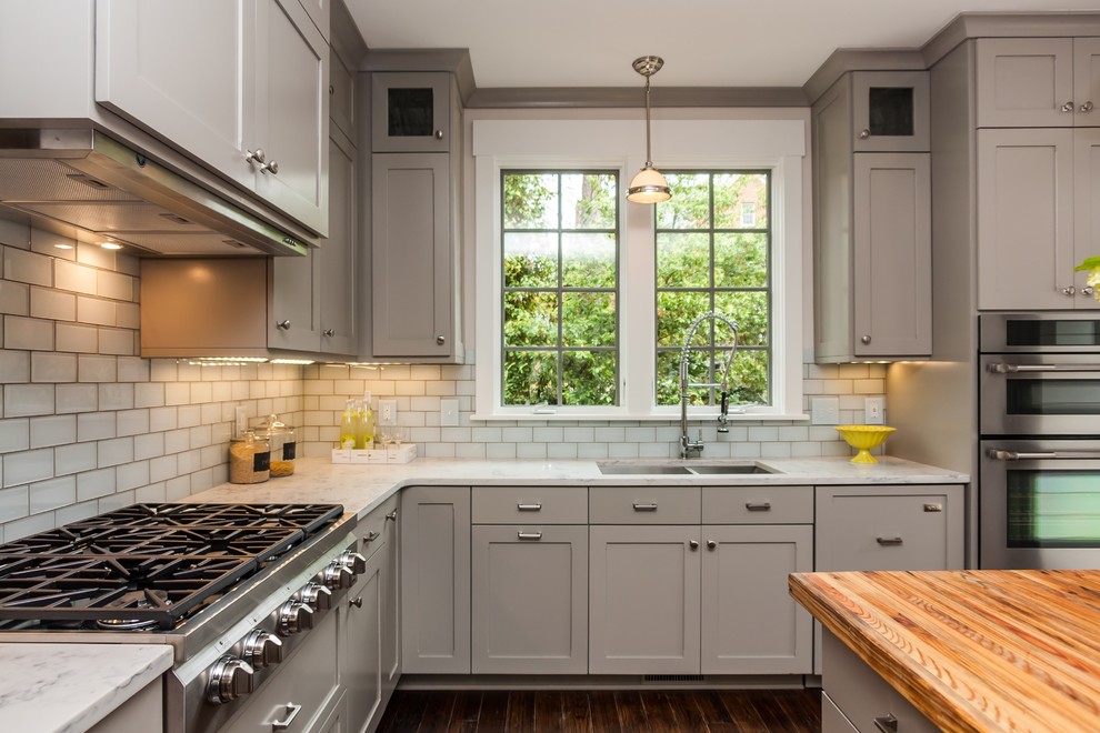 Inspiration for a mid-sized timeless l-shaped dark wood floor eat-in kitchen remodel in Raleigh with an undermount sink, shaker cabinets, gray cabinets, marble countertops, white backsplash, glass tile backsplash, stainless steel appliances and an island