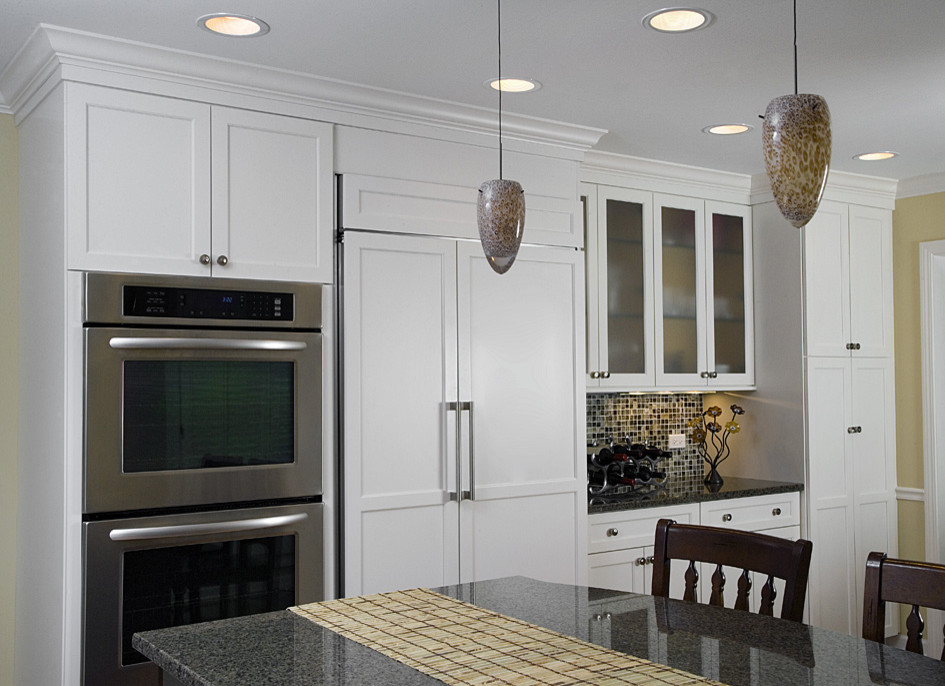 Trendy u-shaped eat-in kitchen photo in Chicago with an undermount sink, shaker cabinets, white cabinets, granite countertops, multicolored backsplash and paneled appliances