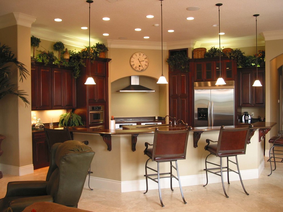Example of a mid-sized classic u-shaped travertine floor open concept kitchen design in Orlando with raised-panel cabinets, medium tone wood cabinets, wood countertops, stainless steel appliances and an island