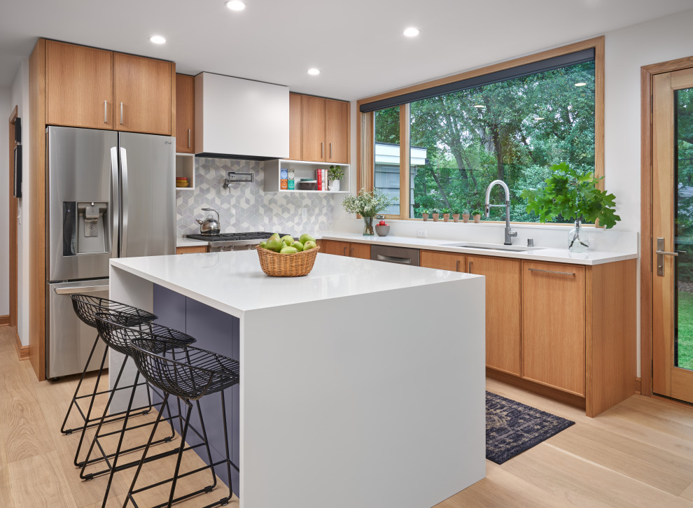 Moderne Wohnküche in L-Form mit Unterbauwaschbecken, flächenbündigen Schrankfronten, hellbraunen Holzschränken, bunter Rückwand, Küchengeräten aus Edelstahl, braunem Holzboden, Kücheninsel, beigem Boden und weißer Arbeitsplatte in Minneapolis