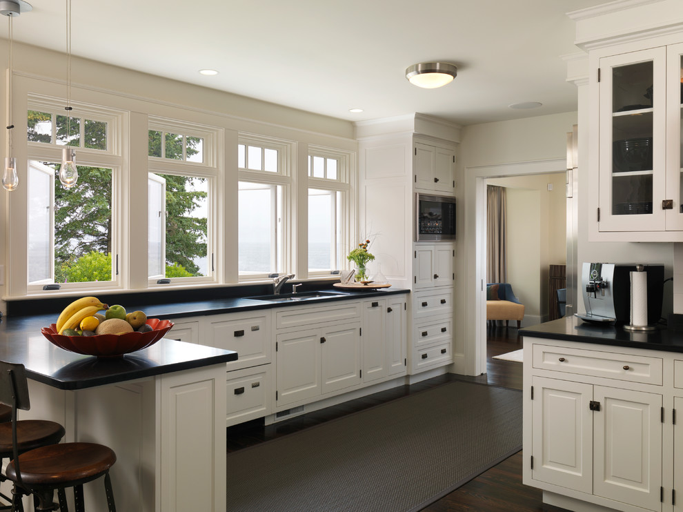 Kitchen - traditional l-shaped kitchen idea in Boston with an undermount sink, white cabinets and black backsplash