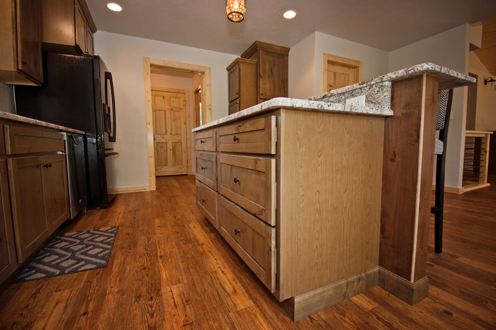 Foto på ett mellanstort rustikt beige kök, med en dubbel diskho, luckor med infälld panel, bruna skåp, granitbänkskiva, rostfria vitvaror, mellanmörkt trägolv, en köksö och brunt golv