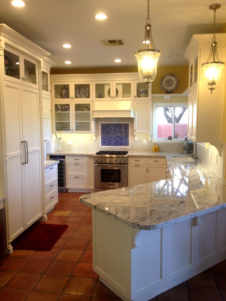 Inspiration for a mid-sized timeless galley terra-cotta tile and brown floor kitchen pantry remodel in Phoenix with an undermount sink, beaded inset cabinets, white cabinets, granite countertops, beige backsplash, porcelain backsplash, paneled appliances and a peninsula