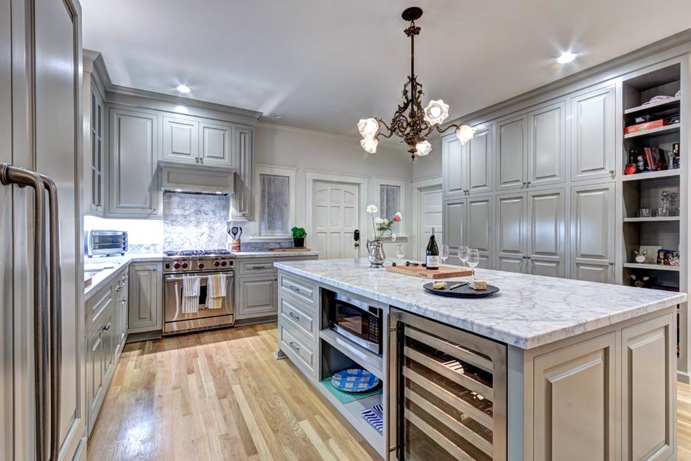 Modern inredning av ett stort u-kök, med luckor med upphöjd panel, grå skåp, marmorbänkskiva, rostfria vitvaror, ljust trägolv och en köksö