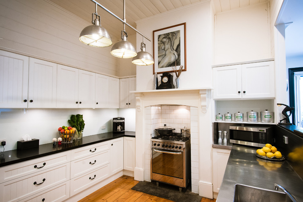 ジーロングにある中くらいなトラディショナルスタイルのおしゃれなキッチン (一体型シンク、落し込みパネル扉のキャビネット、御影石カウンター、白いキッチンパネル、シルバーの調理設備、無垢フローリング) の写真