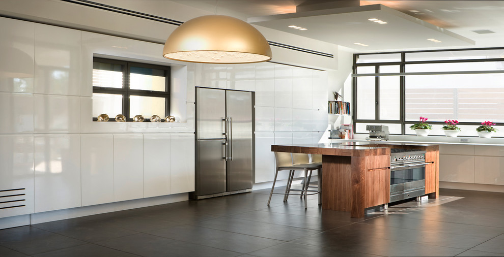 Immagine di una cucina minimalista con elettrodomestici in acciaio inossidabile, top in legno, ante lisce e ante bianche
