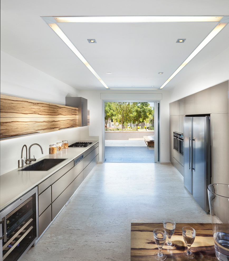 Imagen de cocina contemporánea con armarios con paneles lisos, puertas de armario grises, salpicadero blanco y electrodomésticos de acero inoxidable