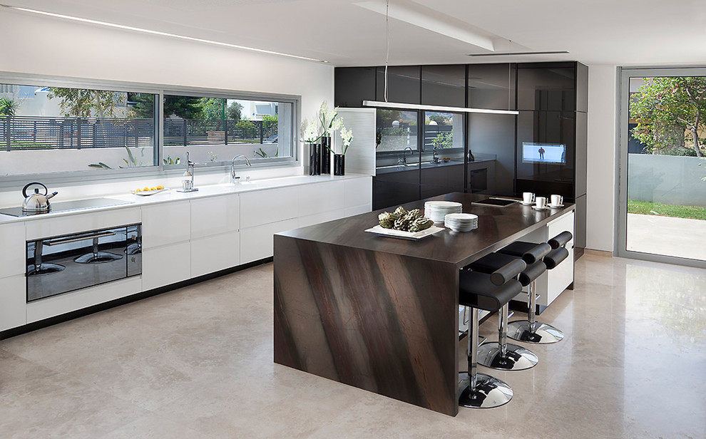 Bild på ett funkis l-kök, med släta luckor, svarta vitvaror och granitbänkskiva