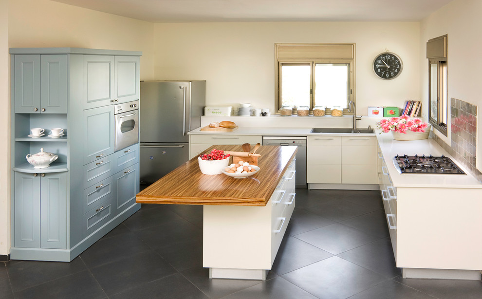 Example of a classic l-shaped kitchen design in Other with wood countertops, stainless steel appliances and blue cabinets