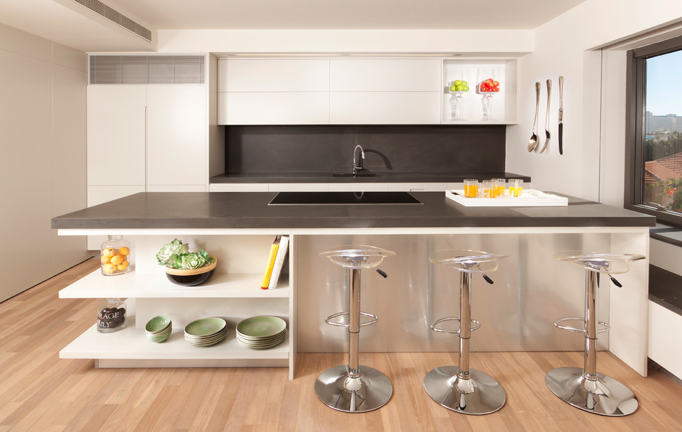 На фото: параллельная кухня в стиле модернизм с плоскими фасадами, белыми фасадами, серым фартуком, техникой под мебельный фасад и барной стойкой