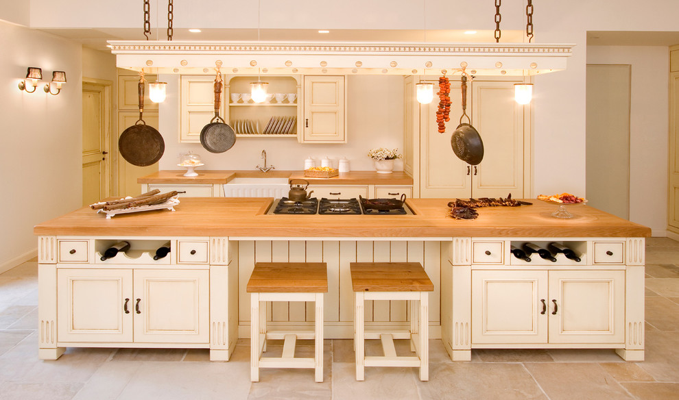Ejemplo de cocina de estilo de casa de campo de obra con encimera de madera, fregadero sobremueble, armarios con paneles empotrados y puertas de armario beige