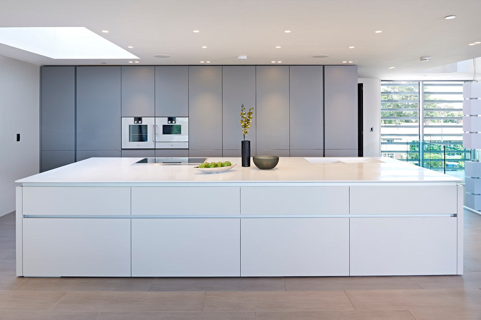 Zweizeilige Moderne Küche mit flächenbündigen Schrankfronten, grauen Schränken, hellem Holzboden und Kücheninsel in Dorset