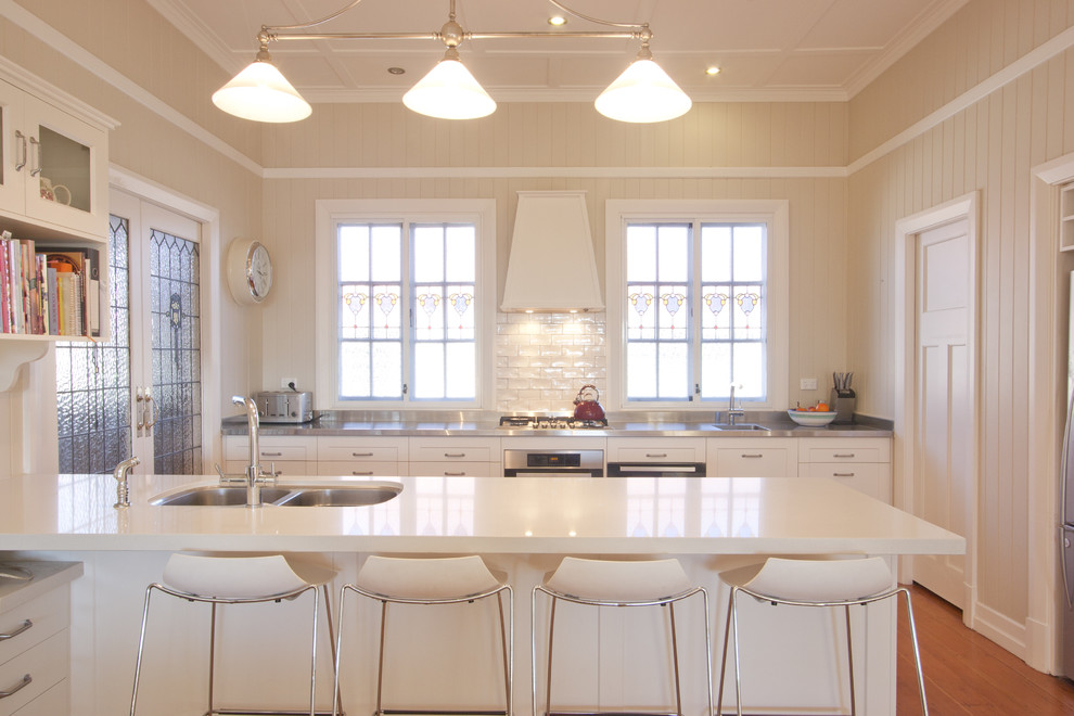 Diseño de cocina contemporánea con armarios con paneles empotrados, electrodomésticos de acero inoxidable, fregadero de doble seno y puertas de armario blancas