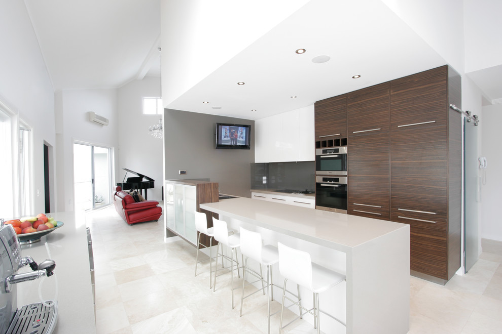 Пример оригинального дизайна: угловая кухня в современном стиле с плоскими фасадами, серым фартуком и диваном