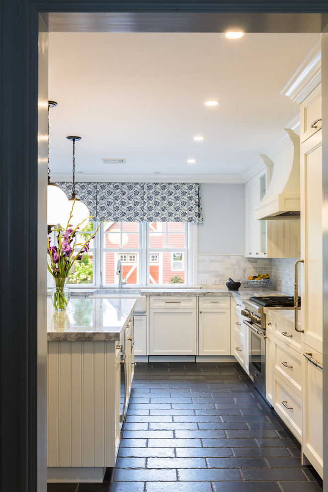 Bild på ett avskilt, mellanstort lantligt u-kök, med en rustik diskho, luckor med infälld panel, vita skåp, granitbänkskiva, vitt stänkskydd, integrerade vitvaror, skiffergolv, en köksö och stänkskydd i tunnelbanekakel