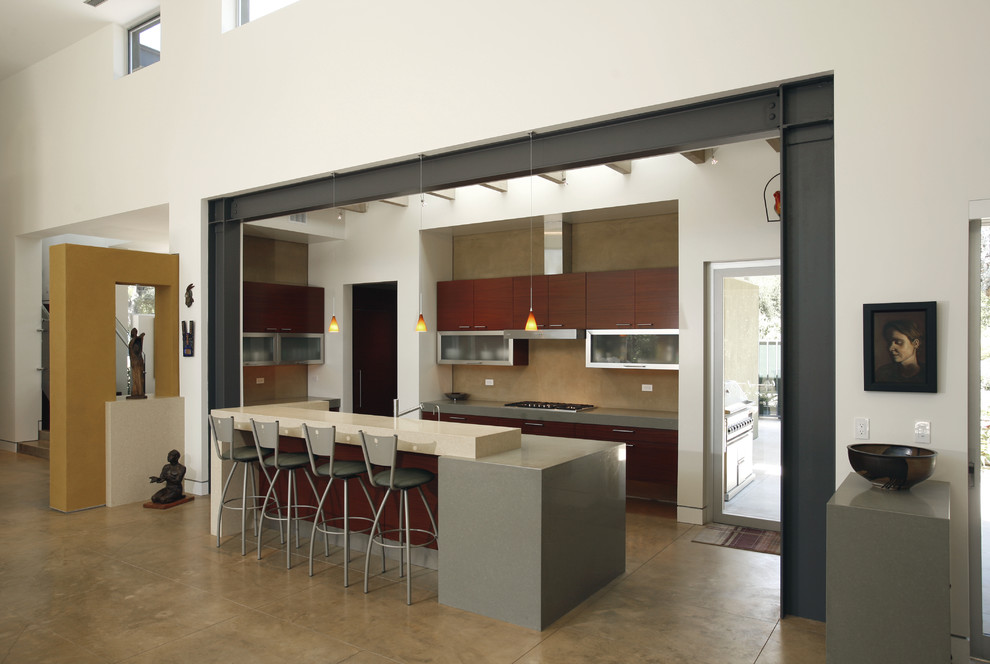 Стильный дизайн: кухня-гостиная в современном стиле с плоскими фасадами, темными деревянными фасадами, столешницей из кварцевого агломерата, бетонным полом и островом - последний тренд