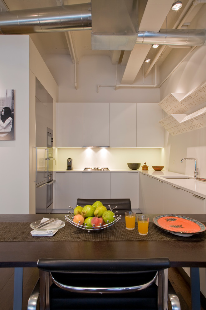 Contemporary u-shaped kitchen/diner in DC Metro with stainless steel appliances, flat-panel cabinets, white cabinets, a submerged sink and engineered stone countertops.