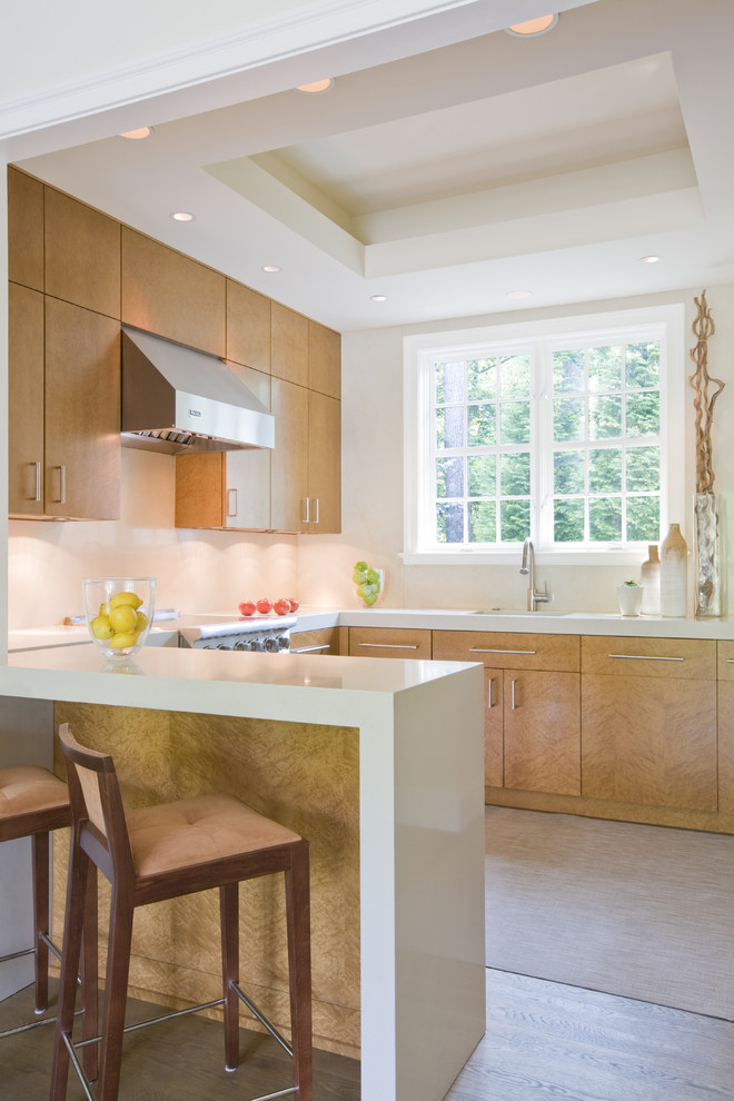 Contemporary u-shaped kitchen/diner in DC Metro with flat-panel cabinets, light wood cabinets, a submerged sink, engineered stone countertops, beige splashback, stone slab splashback and stainless steel appliances.
