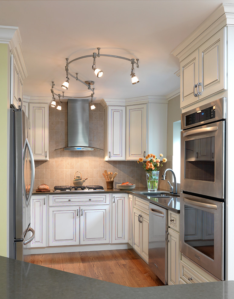 Inspiration for a small transitional u-shaped medium tone wood floor eat-in kitchen remodel in St Louis with an undermount sink, raised-panel cabinets, white cabinets, quartz countertops, gray backsplash, subway tile backsplash, stainless steel appliances and an island