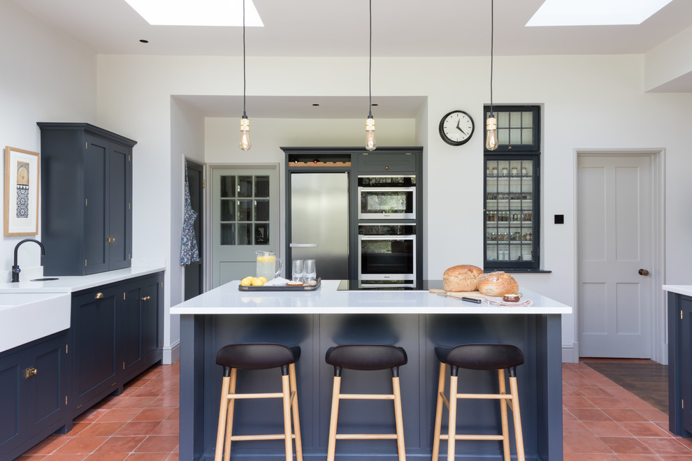 Kitchen/diner in Hertfordshire with a double-bowl sink, shaker cabinets, blue cabinets, an island and white worktops.