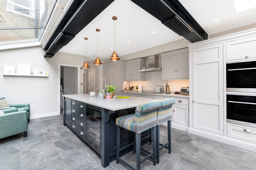 Inspiration for a mid-sized contemporary single-wall concrete floor and gray floor open concept kitchen remodel in London with an integrated sink, shaker cabinets, gray cabinets, concrete countertops, white backsplash, stainless steel appliances and an island