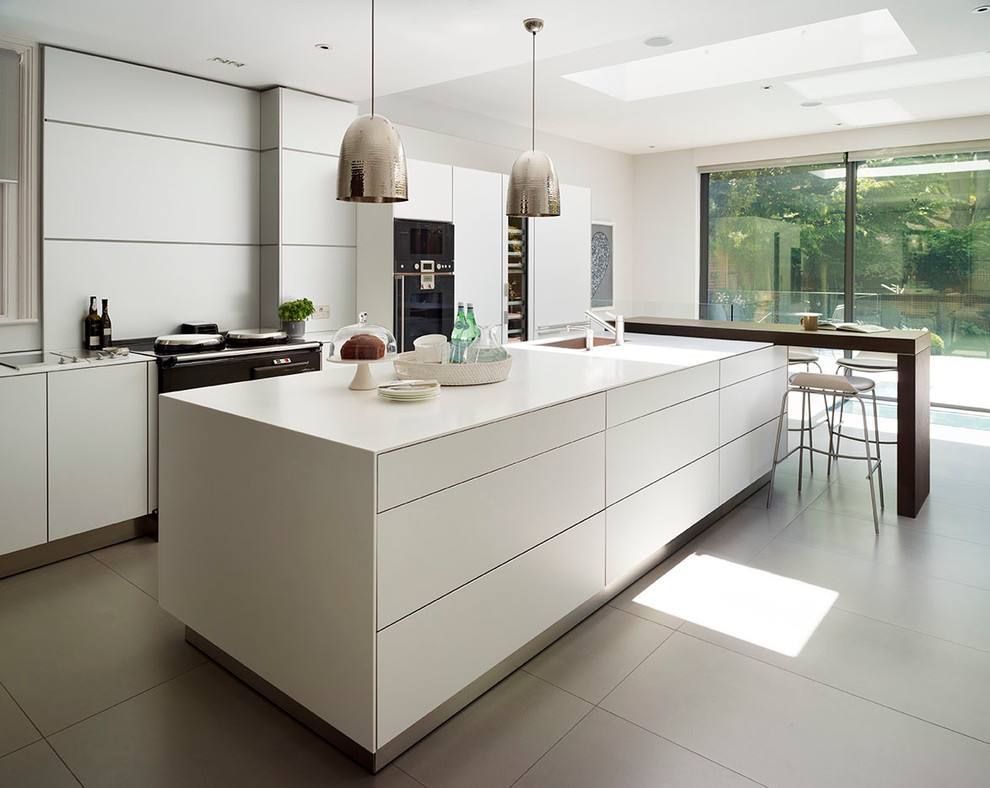 Design ideas for a medium sized contemporary l-shaped kitchen/diner in London with a submerged sink, flat-panel cabinets, white cabinets, composite countertops, metallic splashback, black appliances, porcelain flooring and an island.