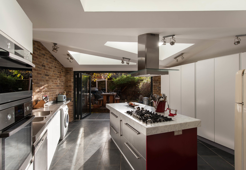 Foto på ett mellanstort funkis linjärt kök och matrum, med en integrerad diskho, släta luckor, skåp i rostfritt stål, marmorbänkskiva, rostfria vitvaror, klinkergolv i keramik och en köksö