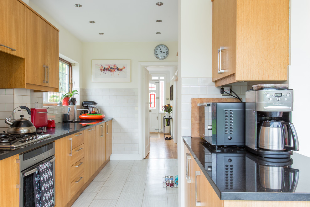 Ejemplo de cocina comedor contemporánea de tamaño medio con fregadero integrado, armarios con paneles lisos, puertas de armario de madera oscura, encimera de granito, salpicadero blanco, salpicadero de azulejos de cerámica, electrodomésticos de acero inoxidable, suelo de baldosas de cerámica y península