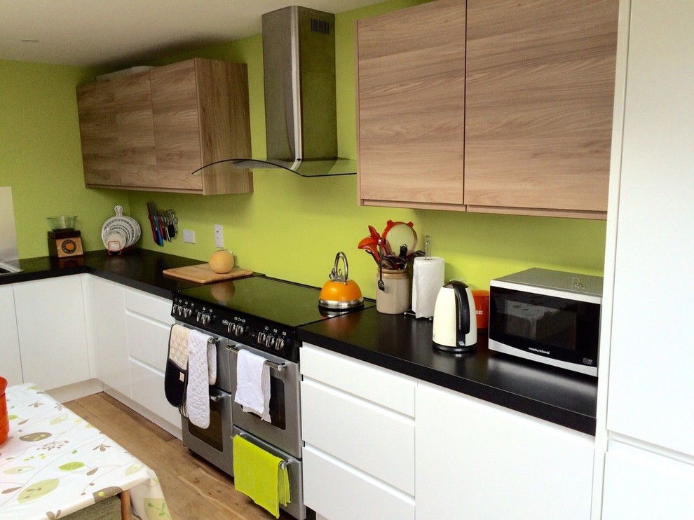 Moderne Wohnküche in L-Form mit Waschbecken, weißen Schränken, Laminat-Arbeitsplatte und hellem Holzboden in Sonstige