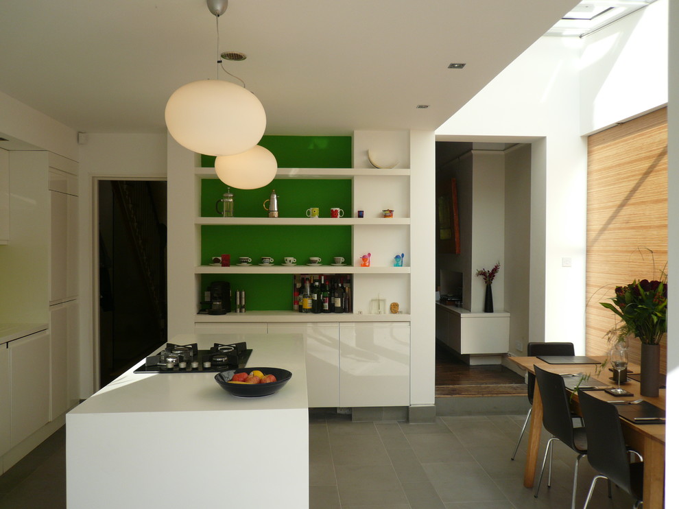 Inspiration pour une cuisine ouverte parallèle minimaliste de taille moyenne avec un placard à porte plane, des portes de placard blanches, un plan de travail en surface solide, une crédence verte, une crédence en feuille de verre et 2 îlots.