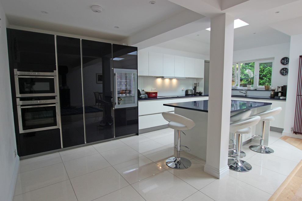This is an example of a modern kitchen in London with glass-front cabinets, engineered stone countertops, stainless steel appliances and an island.