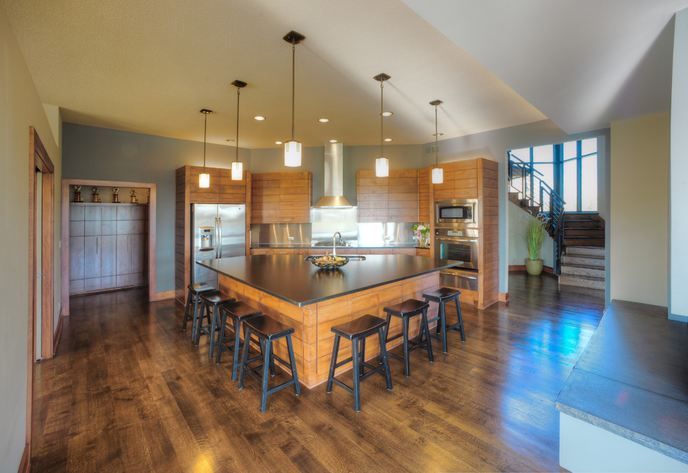 Inspiration for a contemporary u-shaped dark wood floor eat-in kitchen remodel in Kansas City with a drop-in sink, flat-panel cabinets, medium tone wood cabinets, granite countertops, metallic backsplash, stainless steel appliances and an island