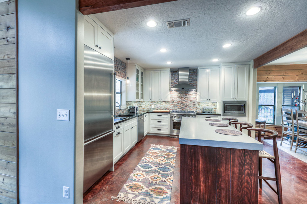Idéer för att renovera ett mellanstort industriellt kök, med luckor med infälld panel, vita skåp, granitbänkskiva, flerfärgad stänkskydd, rostfria vitvaror, en köksö, en undermonterad diskho, stänkskydd i stickkakel, betonggolv och brunt golv