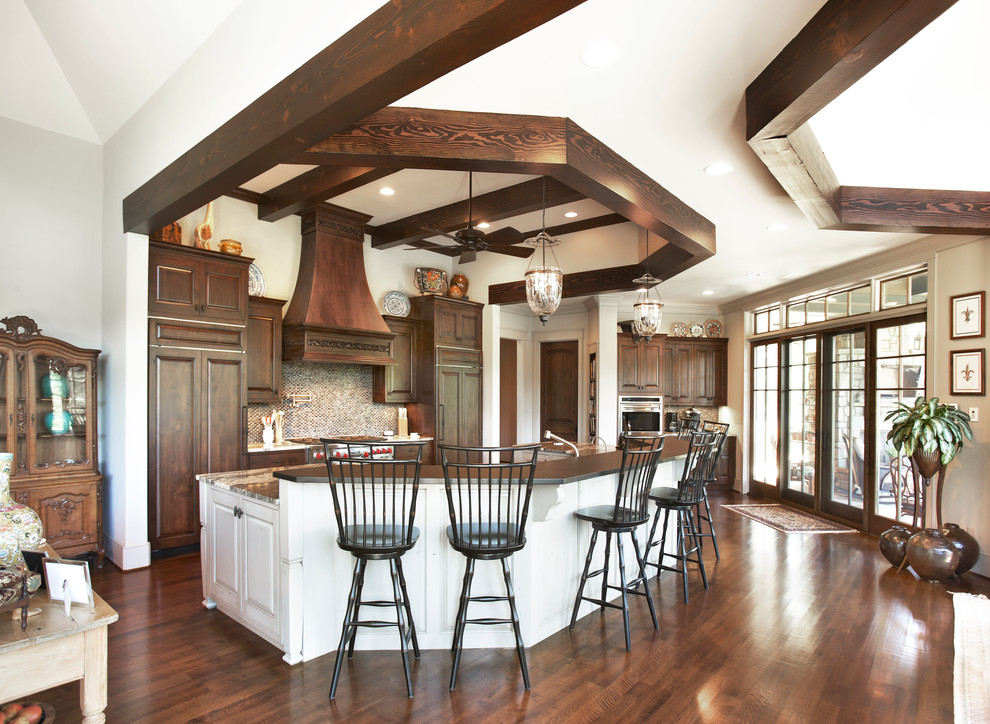 Photo of an expansive traditional galley kitchen/diner in Louisville with raised-panel cabinets, dark wood cabinets, multi-coloured splashback, mosaic tiled splashback, integrated appliances, dark hardwood flooring, an island and brown floors.