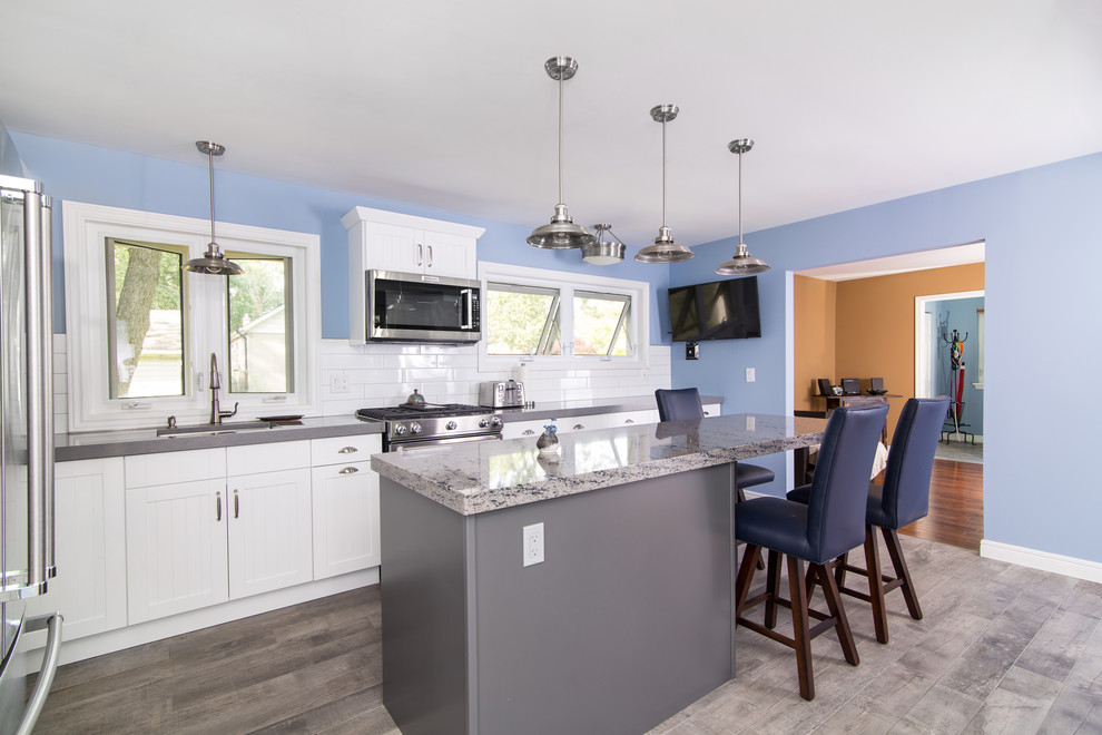Enclosed kitchen - mid-sized transitional l-shaped light wood floor enclosed kitchen idea with an undermount sink, beaded inset cabinets, white cabinets, granite countertops, white backsplash, ceramic backsplash, stainless steel appliances and an island