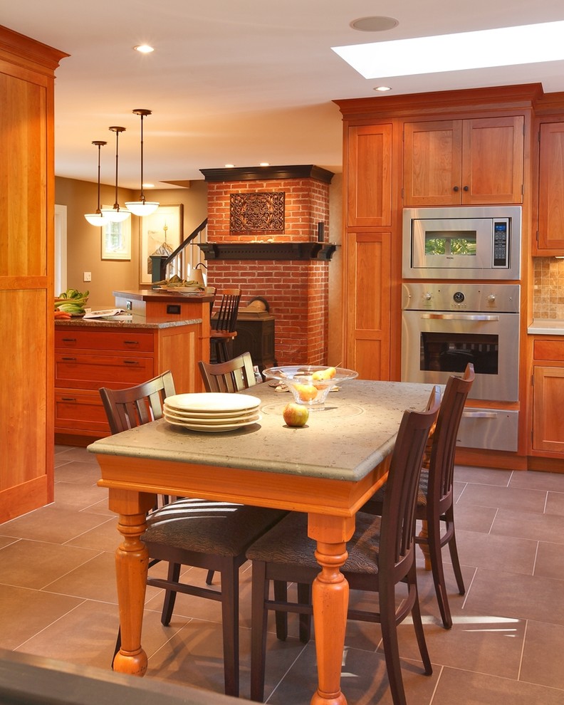 Example of a transitional eat-in kitchen design in Bridgeport with recessed-panel cabinets, medium tone wood cabinets, limestone countertops, beige backsplash, stone tile backsplash and stainless steel appliances