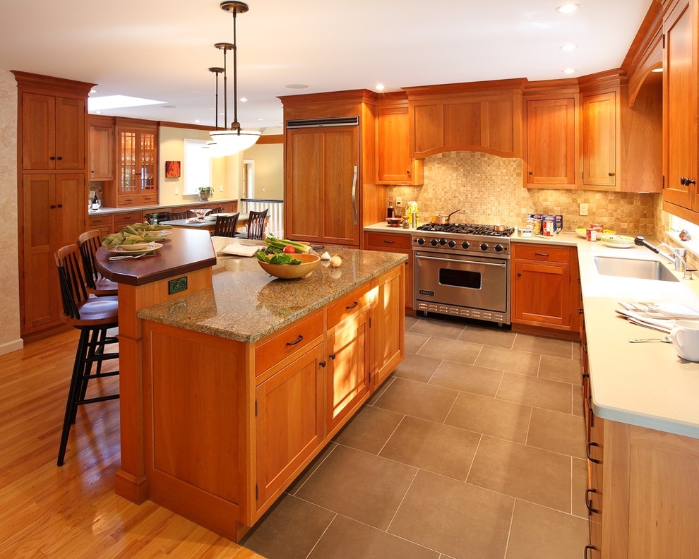 Transitional l-shaped eat-in kitchen photo in Bridgeport with an undermount sink, recessed-panel cabinets, medium tone wood cabinets, granite countertops, beige backsplash, stone tile backsplash and stainless steel appliances