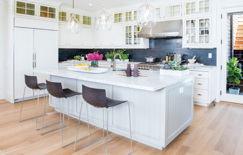 Eat-in kitchen - mid-sized country l-shaped medium tone wood floor and beige floor eat-in kitchen idea in Omaha with a single-bowl sink, white cabinets, quartzite countertops, gray backsplash, stone tile backsplash, paneled appliances and an island
