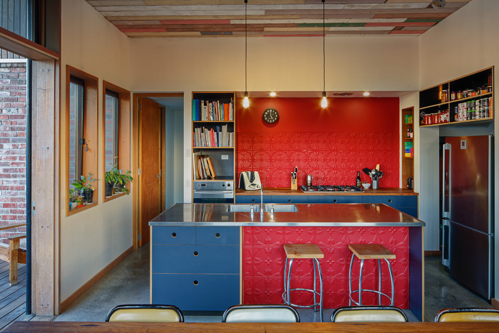 Moderne Küche mit grauen Schränken, Edelstahl-Arbeitsplatte, Kücheninsel, integriertem Waschbecken, Küchengeräten aus Edelstahl und Betonboden in Melbourne